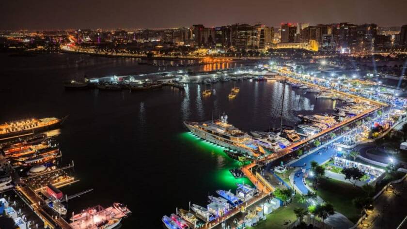 مشهد جوي ليلي لمعرض يخوت فاخرة ومرسى بحري مضاء