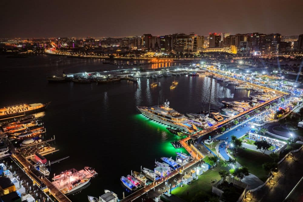 مشهد جوي ليلي لمعرض يخوت فاخرة ومرسى بحري مضاء