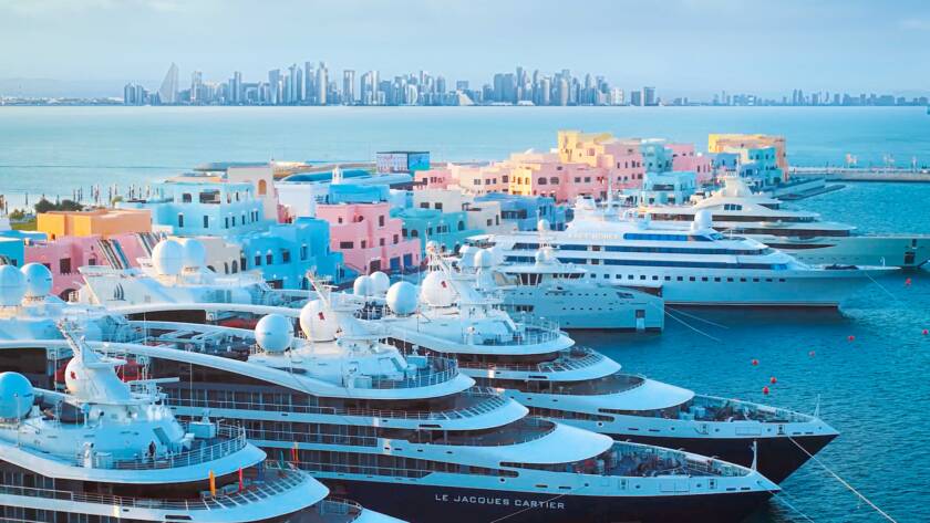Superyachts docked at Old Doha Port with Doha's skyline across the waterfront.